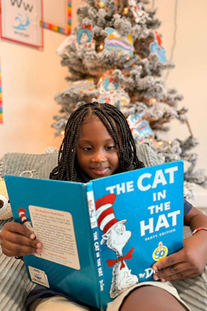 Child smiling while reading at early literacy preschool Miami
