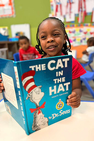 Child practicing reading skills at early literacy preschool Miami