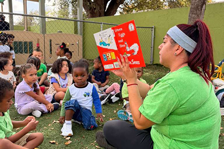 4articulo Teacher reading to children outdoors at SF School - Early Literacy in Miami FL
