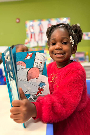 Preschool child reading in classroom at early literacy preschool Miami